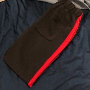 Black track pants with red stripe